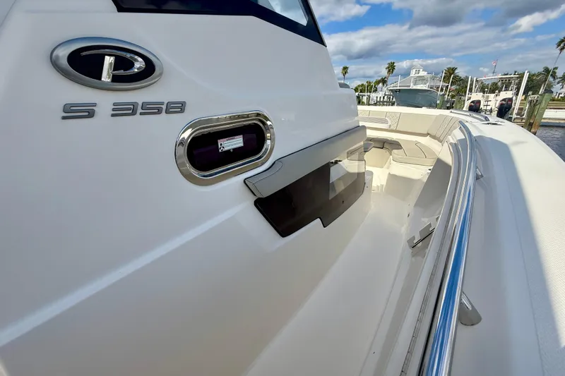  Yacht Photos Pics 2023 Pursuit S 358 Sport boat, sleek design, docked under a partly cloudy sky.