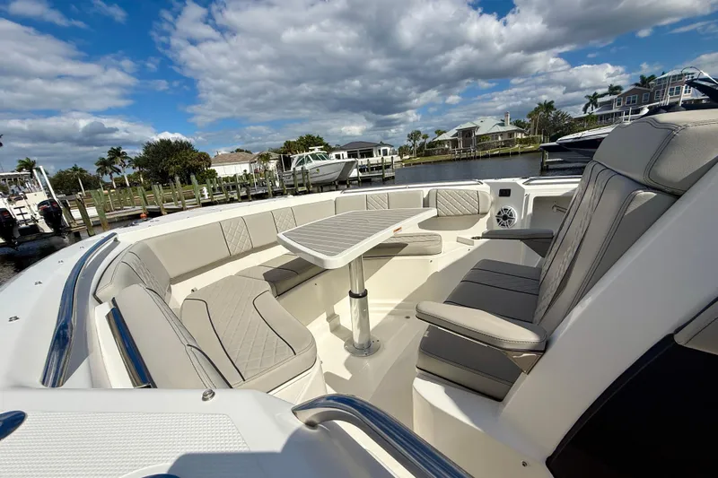  Yacht Photos Pics 2023 Pursuit S 358 Sport boat interior with luxurious seating and table, dockside view.