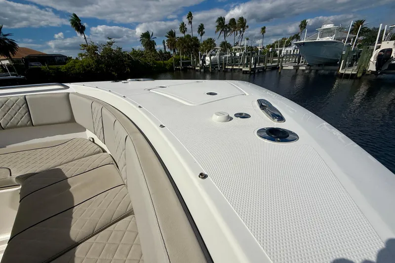  Yacht Photos Pics 2023 Pursuit S 358 Sport boat with beige seating, docked near palm trees and water.