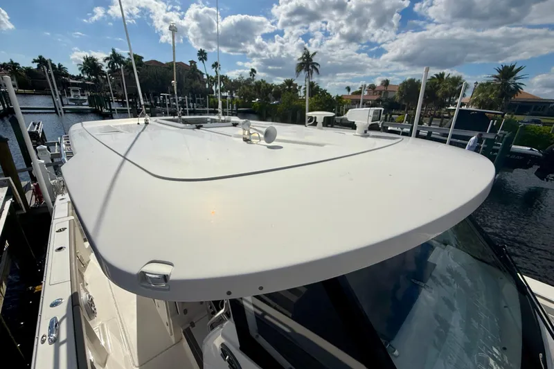  Yacht Photos Pics 2023 Pursuit S 358 Sport boat docked under a sunny sky with palm trees.