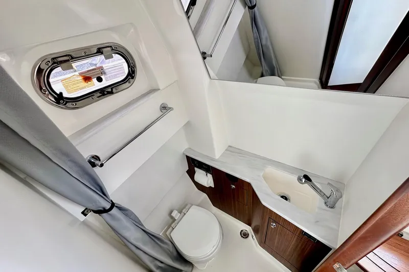  Yacht Photos Pics 2023 Pursuit S 358 Sport boat bathroom with sink, toilet, and porthole window.