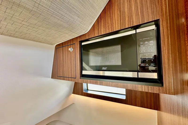  Yacht Photos Pics 2023 Pursuit S 358 Sport interior with built-in microwave and wood paneling.