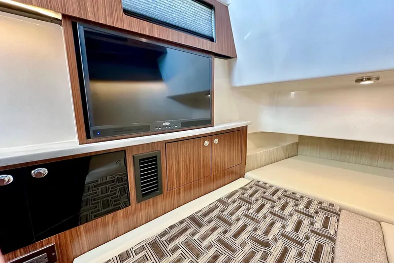  Yacht Photos Pics 2023 Pursuit S 358 Sport interior with TV, wood cabinetry, and modern seating area.