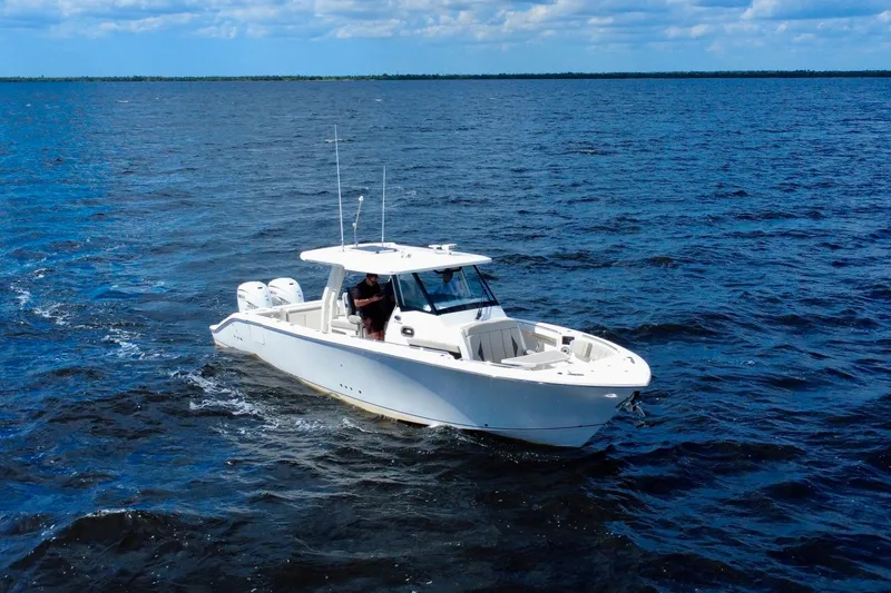  Yacht Photos Pics 2023 Pursuit S 358 Sport boat cruising on open water under a blue sky.