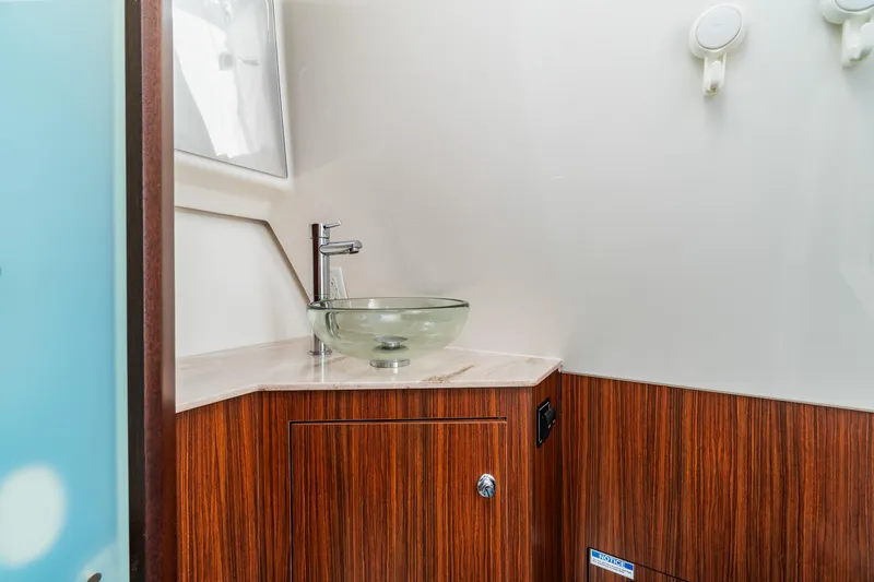 Miss Morgan III Yacht Photos Pics Modern bathroom interior of 2021 Pursuit 365DC boat with glass sink and wood cabinetry.