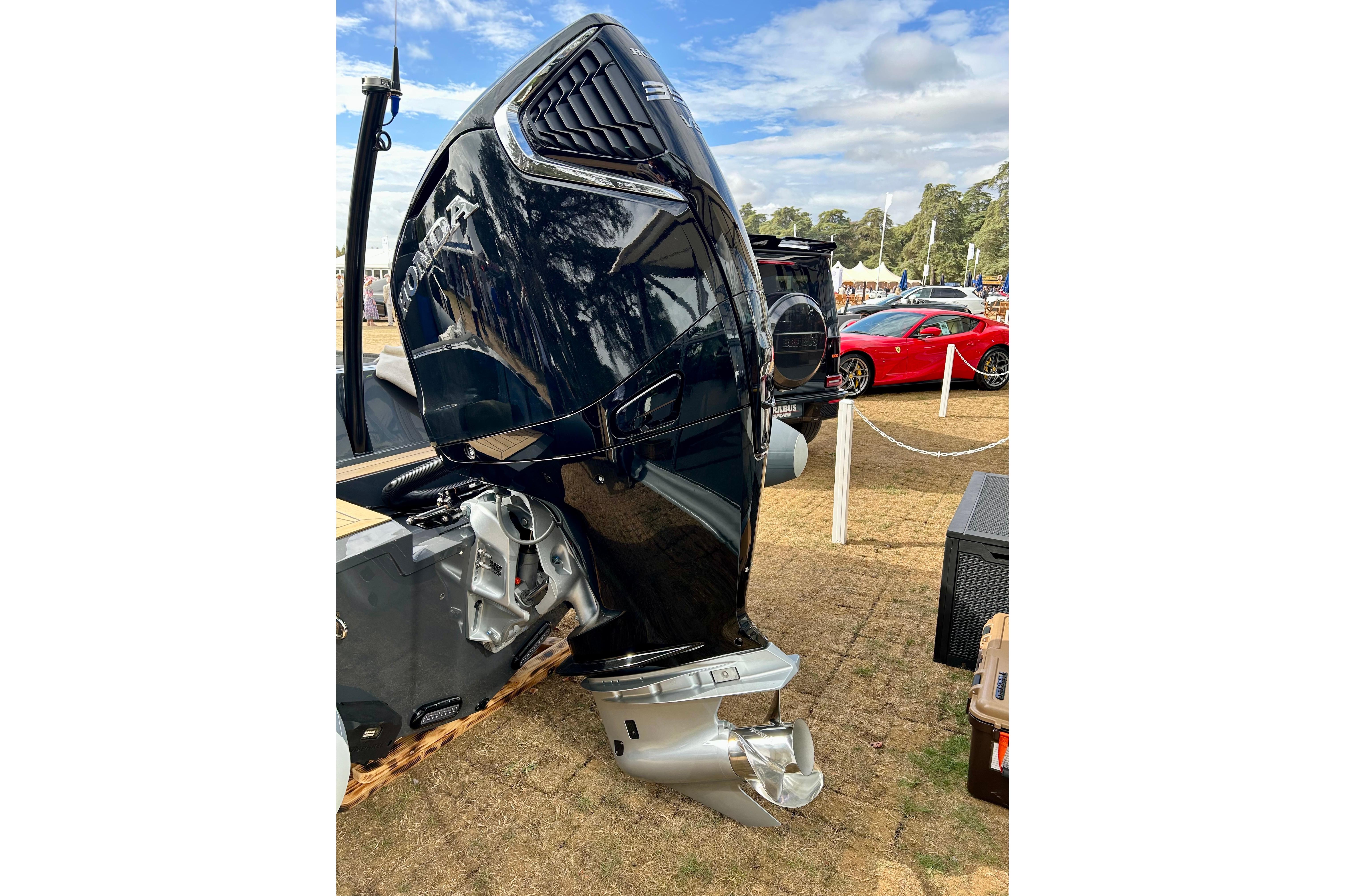 Outboard motor on Twisted 28 Sport 2025 boat, displayed outdoors with cars in background.