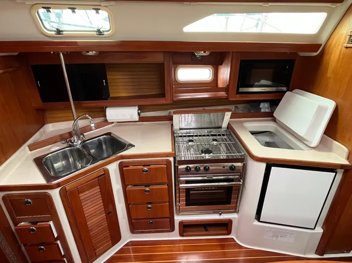 Moonshadow Yacht Photos Pics 1998 Catalina 42 MkII yacht kitchen with wood cabinetry, stainless steel sink, stove, and refrigerator.