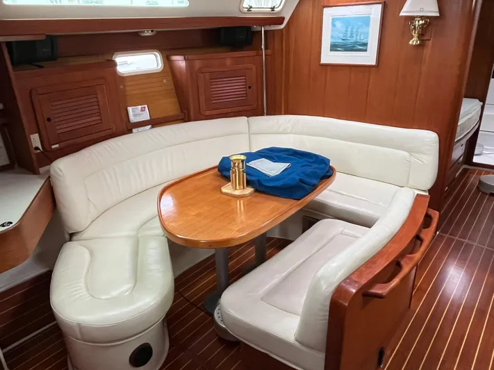 Moonshadow Yacht Photos Pics Cozy interior of 1998 Catalina 42 MkII sailboat with white leather seating and wooden table.
