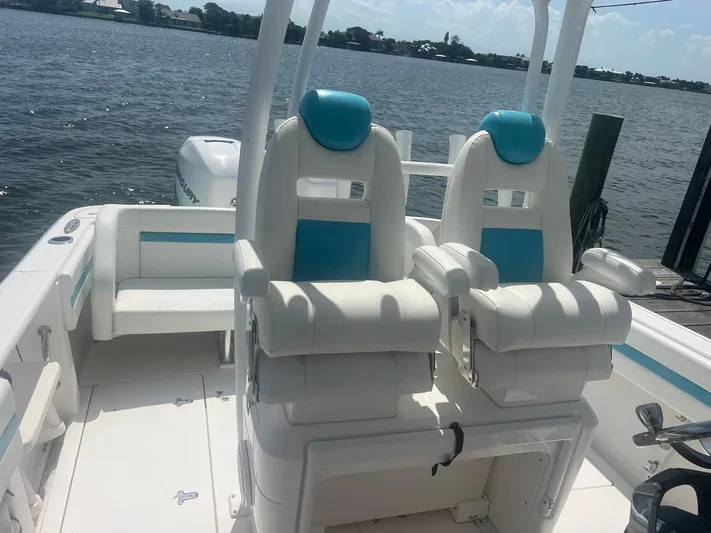  Yacht Photos Pics 2017 Intrepid 327 Cuddy boat interior with white and blue seating, docked by the water.