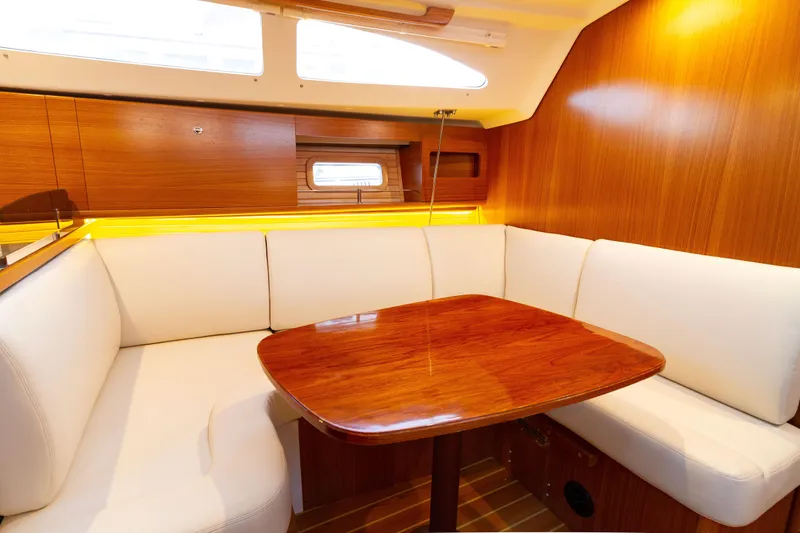 Nordlys Yacht Photos Pics Interior of a 2018 Catalina 315 sailboat with wooden table and white seating.