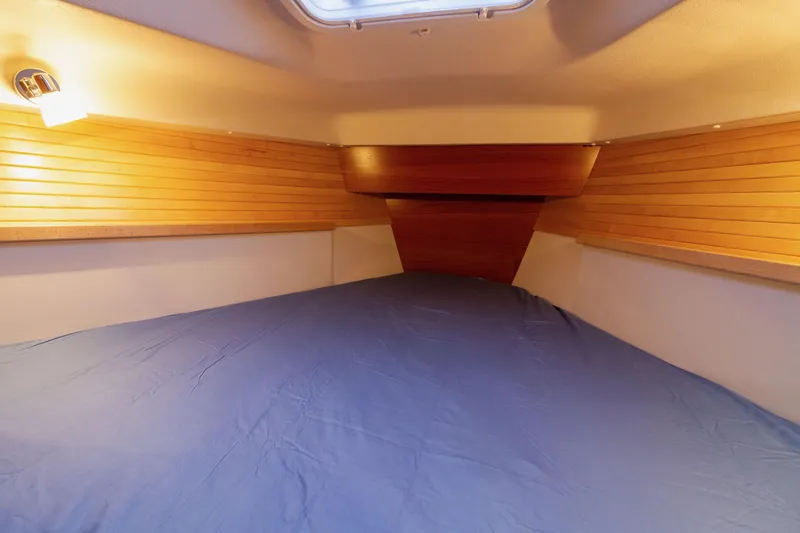 Nordlys Yacht Photos Pics 2018 Catalina 315 interior cabin with wooden paneling and blue bedding.