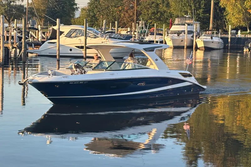  Yacht Photos Pics 2022 Searay SLX350 boat cruising in a marina, surrounded by other docked boats.