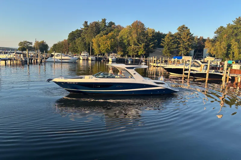  Yacht Photos Pics 2022 Searay SLX350 boat cruising in a scenic marina with surrounding trees.