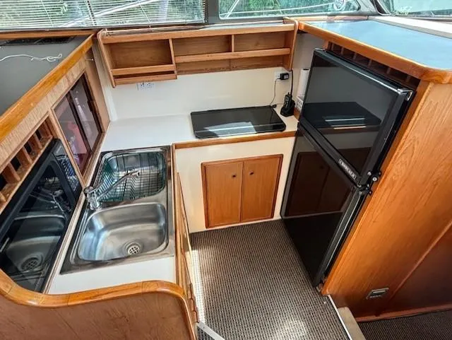 Thunderbolt Yacht Photos Pics 1988 Riviera Convertible yacht kitchen with sink, stove, and fridge in compact layout.