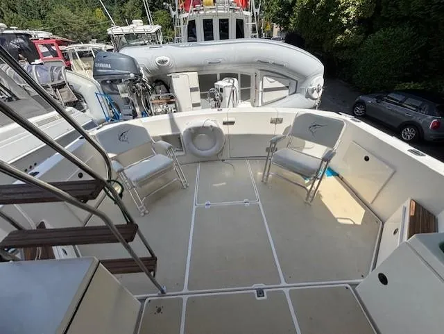 Thunderbolt Yacht Photos Pics 1988 Riviera Convertible boat deck with chairs and equipment, docked near other vessels.