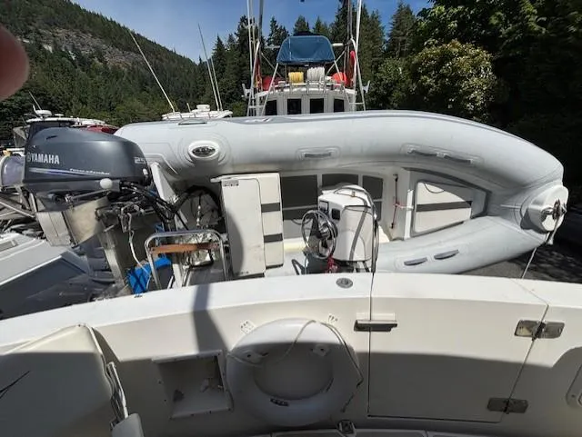 Thunderbolt Yacht Photos Pics 1988 Riviera Convertible with inflatable boat and Yamaha motor, set against a forested backdrop.