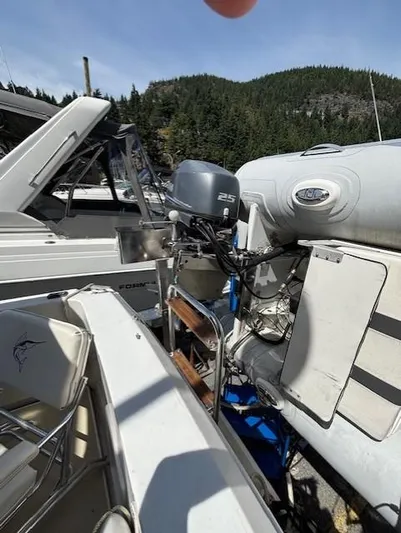 Thunderbolt Yacht Photos Pics 1988 Riviera Convertible boat with outboard motor, docked near inflatable dinghy, forested hills in background.