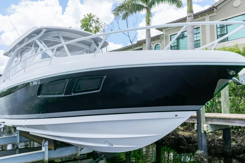  Yacht Photos Pics 2023 Intrepid 345 Valor boat docked near waterfront home, under a clear sky.