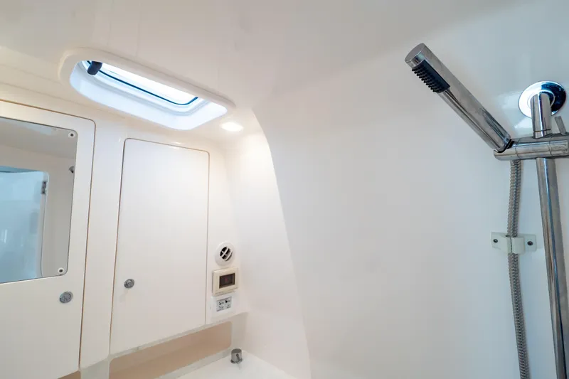  Yacht Photos Pics 2023 Intrepid 345 Valor bathroom with showerhead, skylight, and storage cabinets.