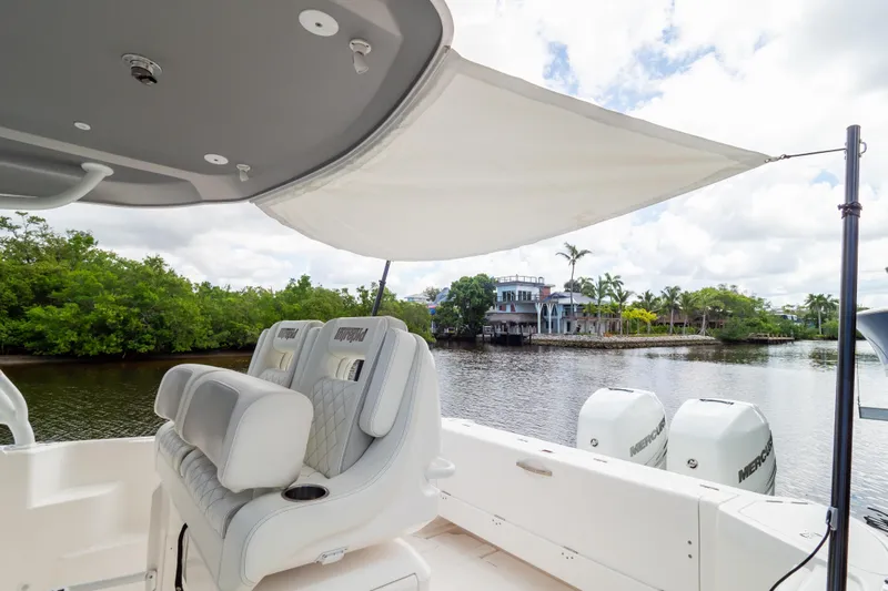  Yacht Photos Pics 2023 Intrepid 345 Valor boat interior with seating, canopy, and scenic waterfront view.