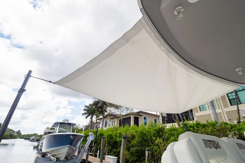  Yacht Photos Pics 2023 Intrepid 345 Valor boat with sunshade, docked near waterfront homes.