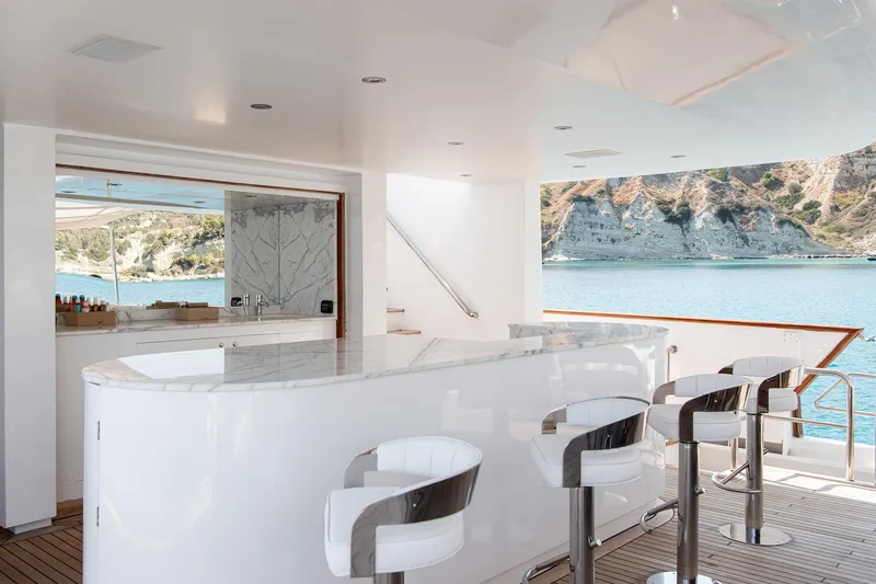 Koru Yacht Photos Pics Luxurious yacht bar area with ocean view, featuring sleek stools and marble countertop. Feadship Custom 1983.