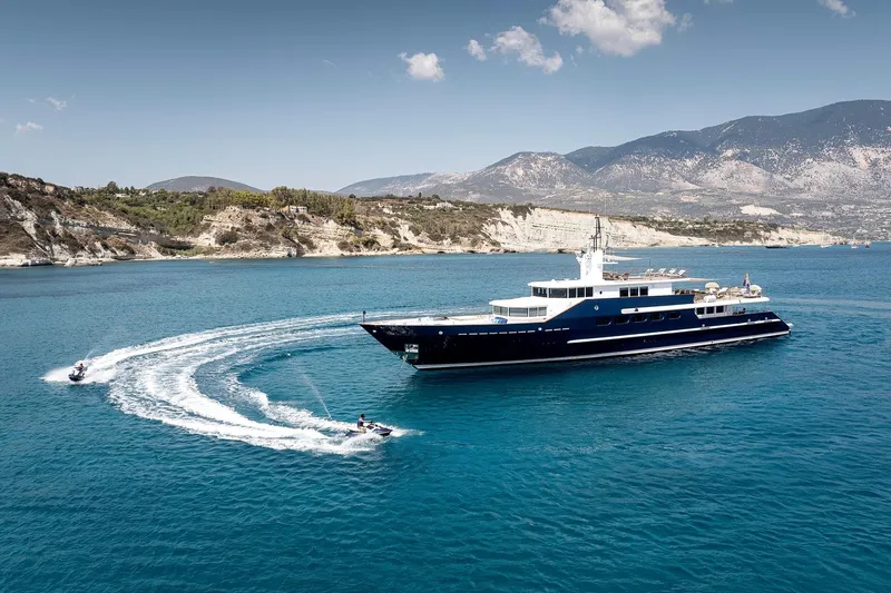 Koru Yacht Photos Pics Luxury 1983 Feadship Custom yacht cruising with jet skis in scenic coastal waters.