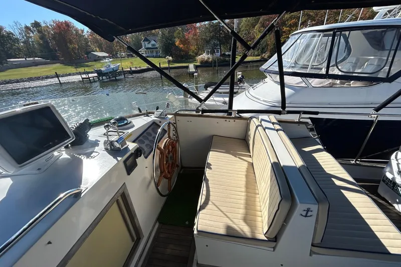 Radius Yacht Photos Pics 1986 Grand Banks 42 Classic yacht cockpit with seating and steering wheel, docked by a scenic waterfront.