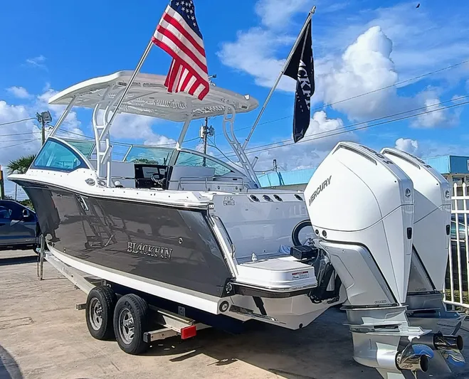 272-292 Yacht Photos Pics 2024 Blackfin 272 DC boat with dual Mercury engines on a trailer, flags waving.