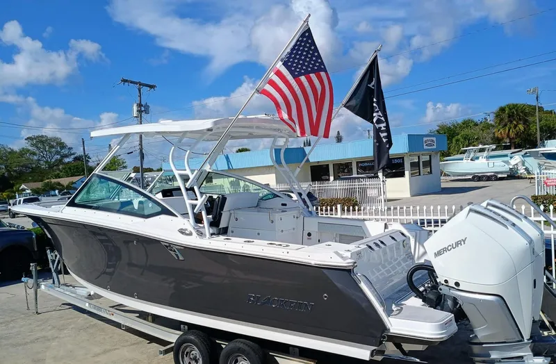272-292 Yacht Photos Pics 2024 Blackfin 272 DC boat on trailer with American flag, Mercury engine, and clear blue sky.