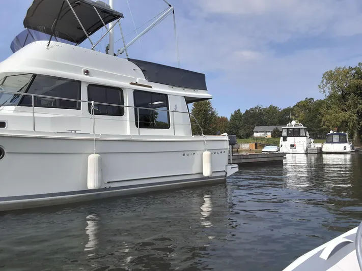  Yacht Photos Pics 2014 Beneteau Swift Trawler 34 docked on calm water, with other boats nearby.