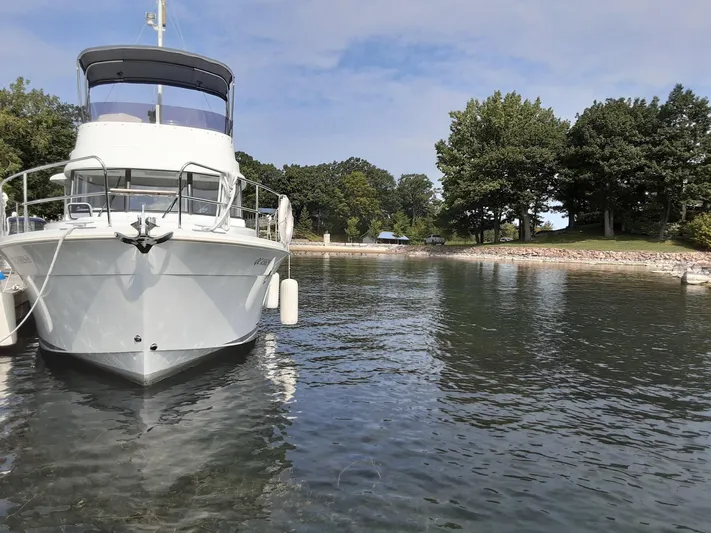  Yacht Photos Pics 2014 Beneteau Swift Trawler 34 docked in a serene, tree-lined harbor.
