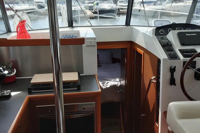  Yacht Photos Pics Interior of 2014 Beneteau Swift Trawler 34, featuring helm, kitchen, and cabin entrance.