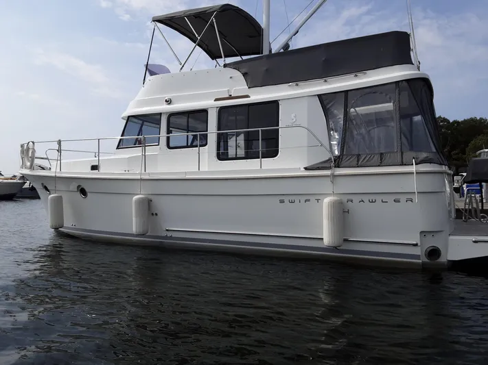  Yacht Photos Pics 2014 Beneteau Swift Trawler 34 on water, side view with canopy and fenders.