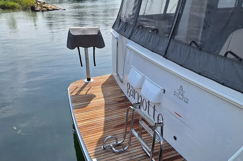  Yacht Photos Pics 2014 Beneteau Swift Trawler 34 with wooden deck and grill, docked by calm water.