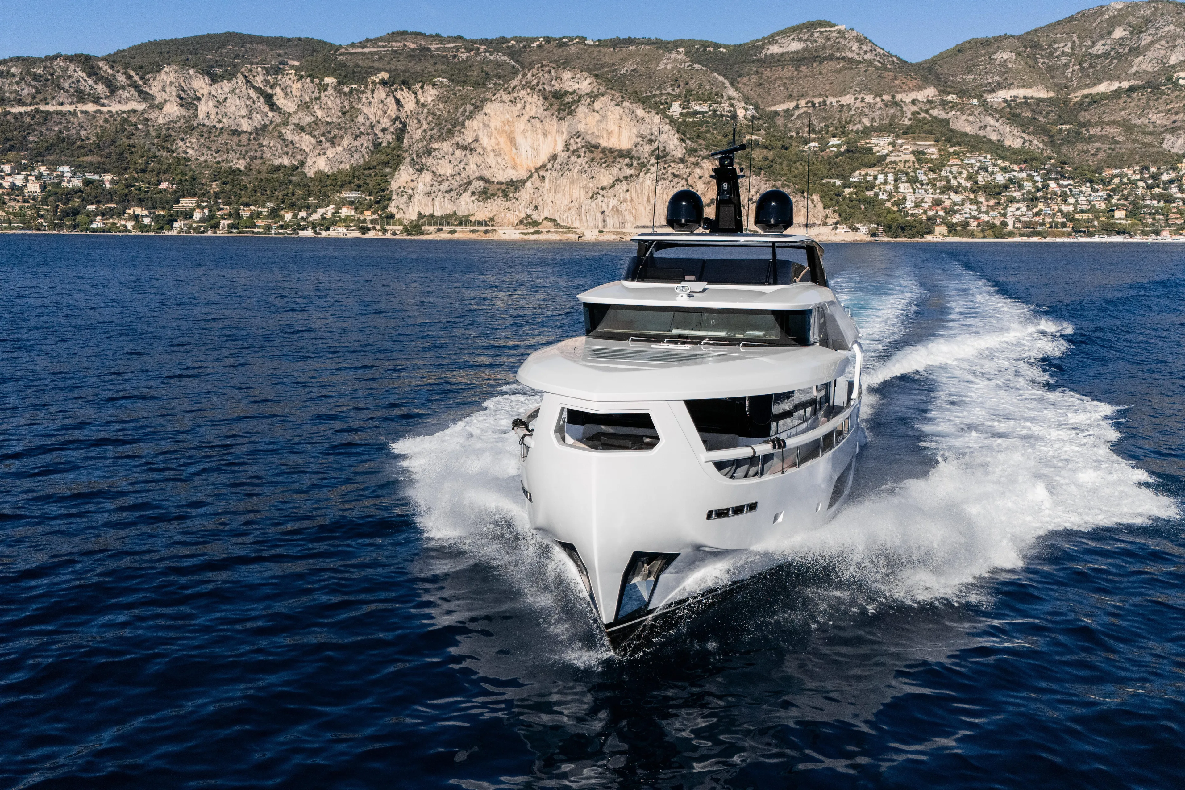  Yacht Photos Pics 2025 Ferretti Yachts INFYNITO 80 cruising on blue ocean with scenic mountain backdrop.