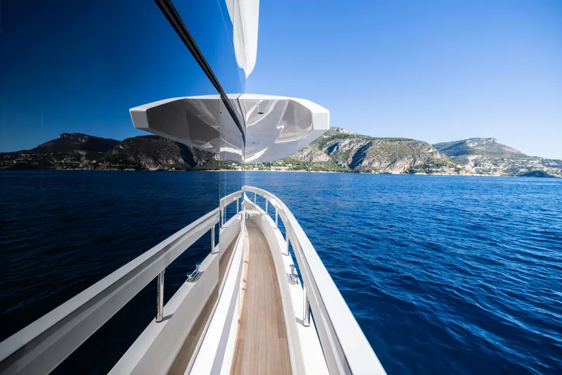  Yacht Photos Pics 2025 Ferretti Yachts INFYNITO 80 cruising on blue ocean with scenic mountain backdrop.