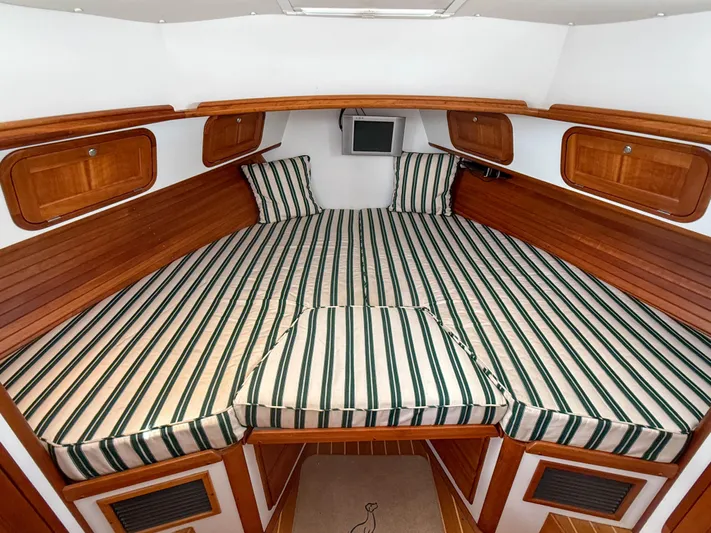 Waypoint Yacht Photos Pics 2002 Legacy 34 Express cabin with striped bedding and wooden accents.