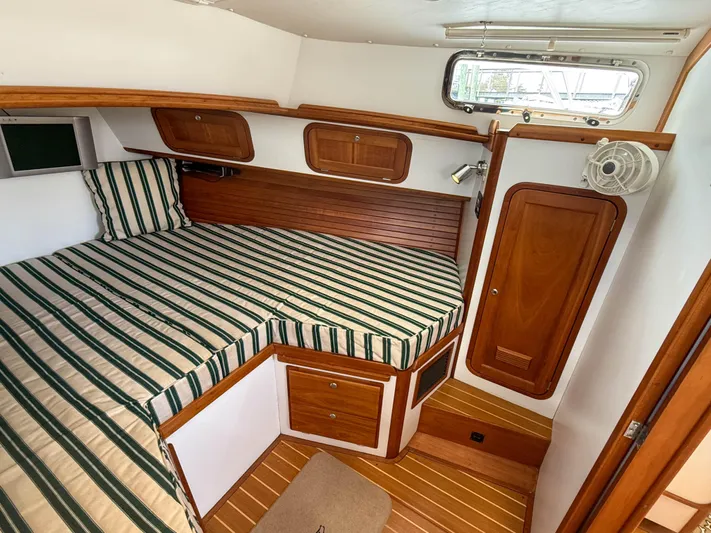 Waypoint Yacht Photos Pics 2002 Legacy 34 Express cabin with striped bedding and wooden interior.