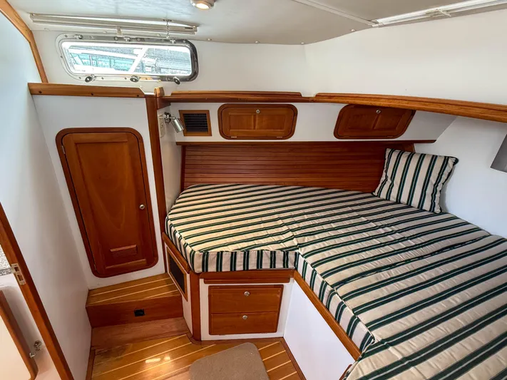 Waypoint Yacht Photos Pics 2002 Legacy 34 Express cabin with striped bedding and wooden cabinetry.