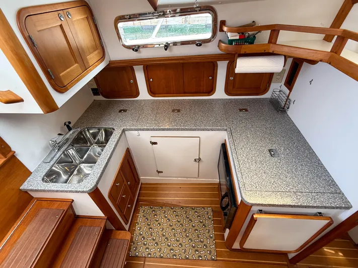 Waypoint Yacht Photos Pics 2002 Legacy 34 Express boat kitchen with wooden cabinets and granite countertops.