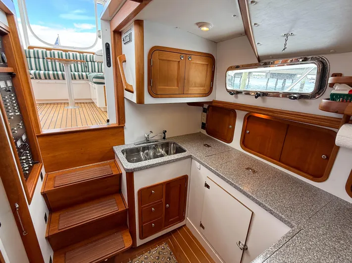 Waypoint Yacht Photos Pics 2002 Legacy 34 Express yacht interior with wooden cabinetry and compact kitchen area.