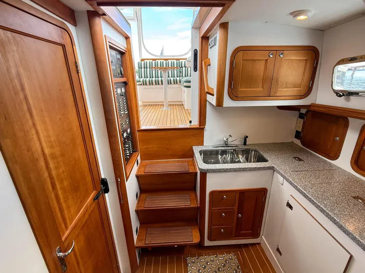 Waypoint Yacht Photos Pics Interior of 2002 Legacy 34 Express boat with wooden cabinetry and compact kitchen area.