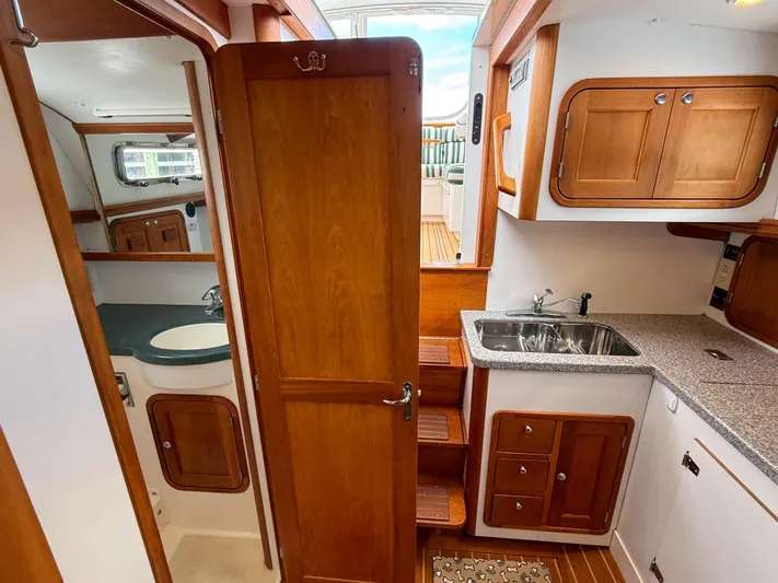 Waypoint Yacht Photos Pics Interior of 2002 Legacy 34 Express boat with wooden cabinetry and compact kitchen area.