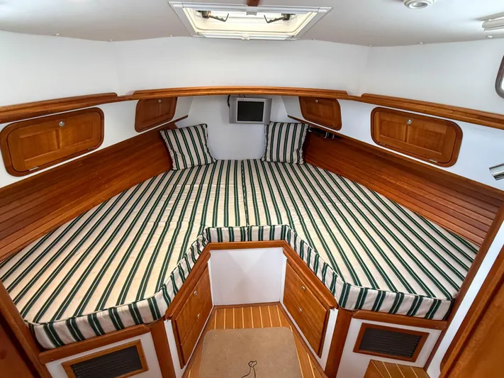 Waypoint Yacht Photos Pics 2002 Legacy 34 Express cabin with striped bedding and wooden accents.