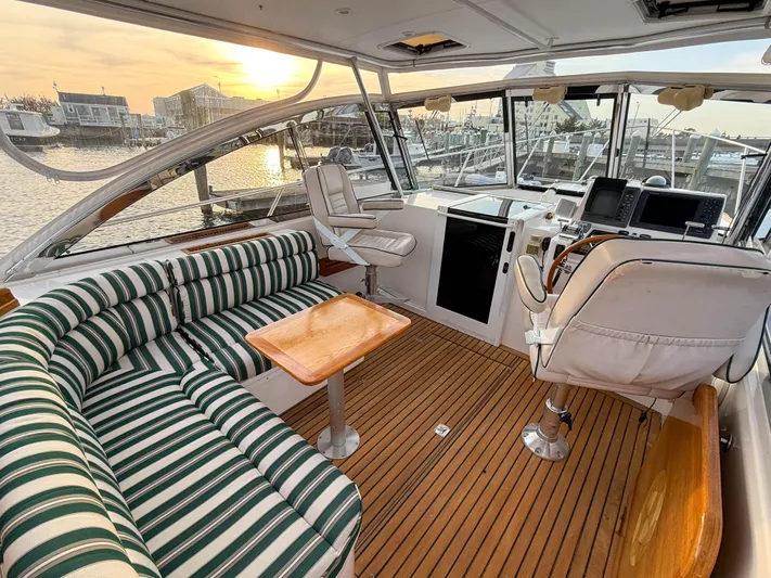Waypoint Yacht Photos Pics Interior of 2002 Legacy 34 Express yacht with striped seating and wooden flooring at sunset.