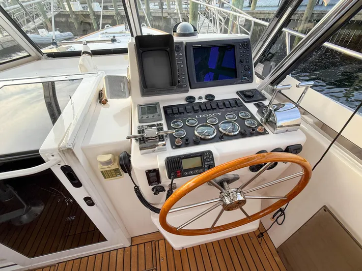 Waypoint Yacht Photos Pics Helm of 2002 Legacy 34 Express boat with navigation instruments and wooden steering wheel.