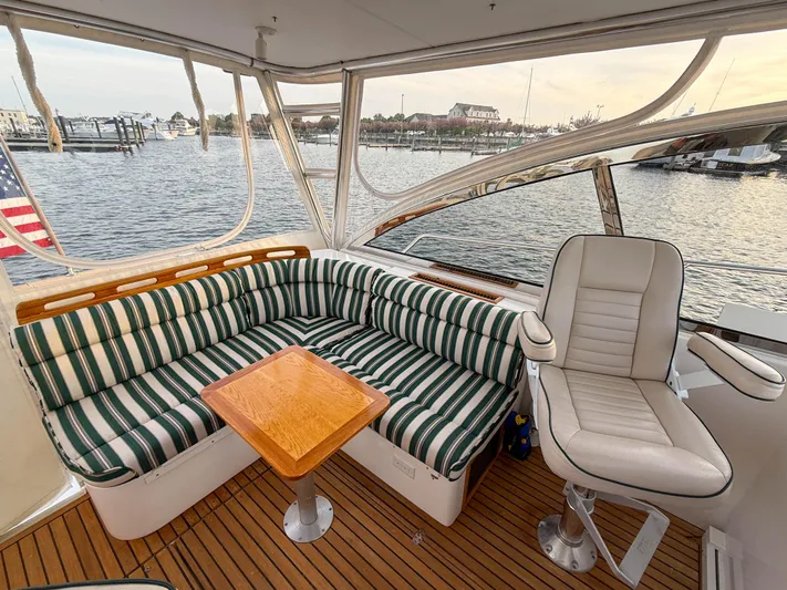 Waypoint Yacht Photos Pics 2002 Legacy 34 Express yacht interior with striped seating and wooden table, overlooking marina.