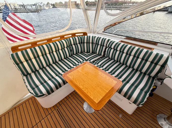 Waypoint Yacht Photos Pics Cozy seating area on 2002 Legacy 34 Express boat with striped cushions and wooden table.