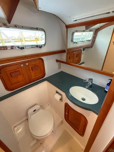 Waypoint Yacht Photos Pics 2002 Legacy 34 Express yacht bathroom with sink, toilet, and wooden cabinetry.